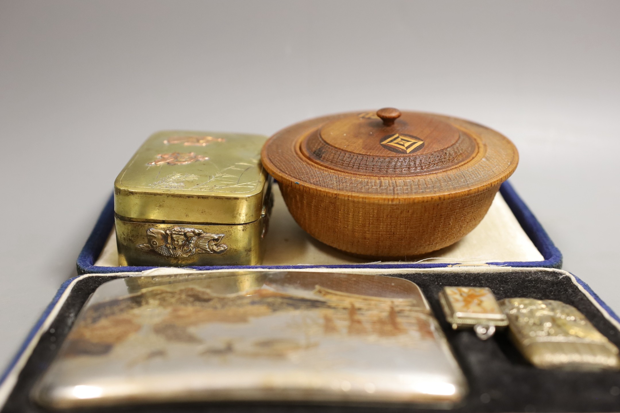 A Japanese sterling cigarette case, vesta, a locket, box and carved circular bowl and cover, bowl and cover 11 cms diameter.